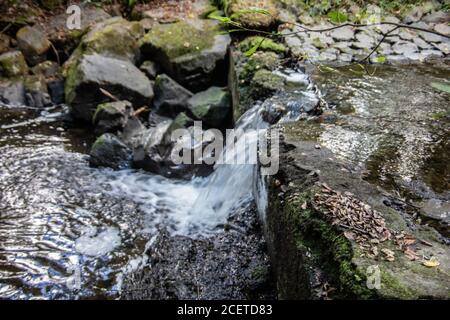 Flusslauf übersät mit Felsen mit Wasserfall im Siegerland Stockfoto