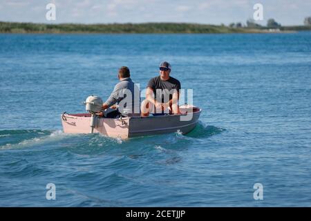 Zwei Männer in einem kleinen Boot mit Außenbordantrieb auf einem See. Stockfoto