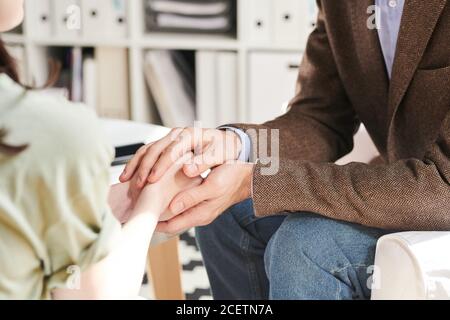 Unkenntlich Psychologin tröstende junge Frau berührt ihre Hände auf Therapie-Sitzung, Nahaufnahme Stockfoto