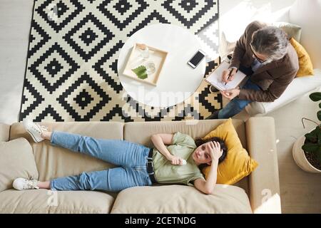 Direkt von oben Ansicht Aufnahme der fröhlichen jungen Frau liegend Auf dem Sofa während der Psychotherapie Stockfoto