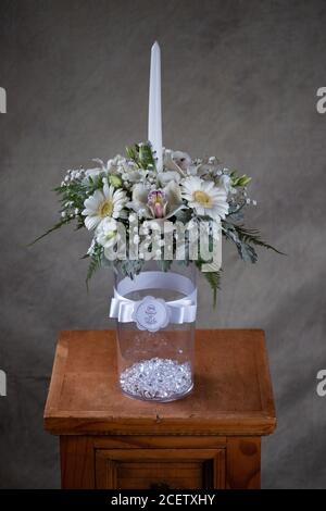 Erste heilige Kommunion Blumensträuße. Weiße Kerze mit Orchidee und Blumen weißen Blumen verziert. Stockfoto