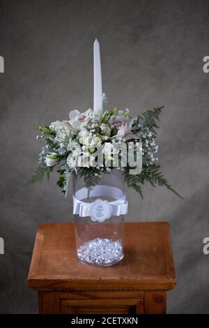 Erste heilige Kommunion Blumensträuße. Weiße Kerze mit Orchidee und Blumen weißen Blumen verziert. Stockfoto