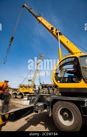 Taraz/Kasachstan - April 25 2012: Renovierung der Phosphordüngeanlage. LKW-Kran mit Fahrer und Trägerkran bei der Arbeit. Stockfoto