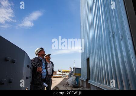 Taraz/Kasachstan - April 25 2012: Phosphordüngeanlage. Zwei Ingenieure schauen auf neues Industriegebäude. Stockfoto