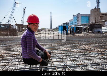 Taraz/Kasachstan - April 25 2012: Modernisierung der Phosphatdüngeanlagen. Junge Arbeiterin Frau auf Fabrik Hintergrund. Betonbewehrung für Basis Stockfoto