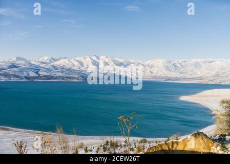 Erstaunlich schöne Winterlandschaft von Charvak Stausee in Usbekistan in Winter mit blauem Wasser darin Stockfoto