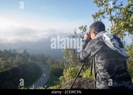 Männlicher Fotograf, der die Berglandschaft des Sonnenaufgangs in Chiang Mai, Thailand, fotografiert. Stockfoto