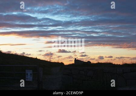 Schöner rosa und orange Sonnenuntergang in der Landschaft mit hübschen Wolken von Trefor, North Wales gesehen Stockfoto