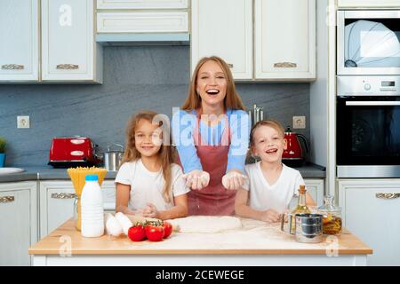 Junge blonde Frau, Mutter und ihre Kinder haben Spaß beim Kochen Teig Stockfoto