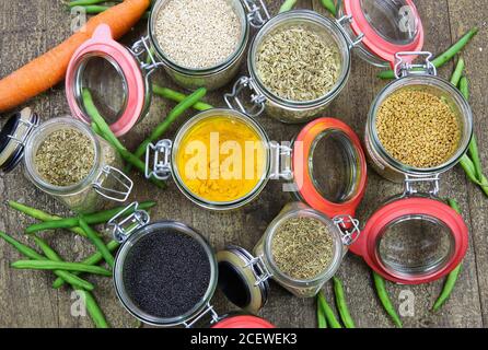 Draufsicht auf isolierte Einmachgläser mit Vielfalt an bunten Condiments auf Holztisch - Kunststoff-freies Verpackungskonzept Stockfoto
