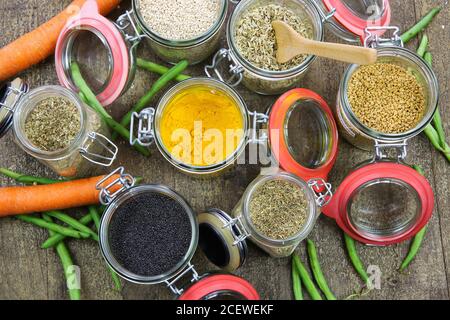 Draufsicht auf isolierte Einmachgläser mit Vielfalt an bunten Condiments auf Holztisch - Kunststoff-freies Verpackungskonzept Stockfoto