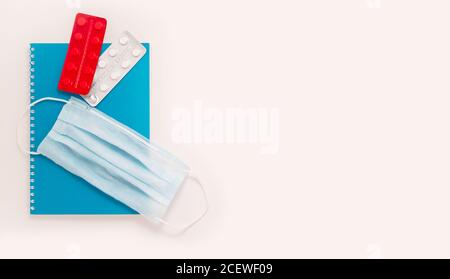 Bleiben Sie zu Hause weißen Hintergrund flach. Home Office medizinische Maske blau Notebook rot weiß Tabletten Streifen Draufsicht Stockfoto