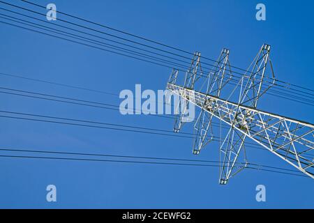 Strommast mit Drähten gegen blauen Himmel Stockfoto