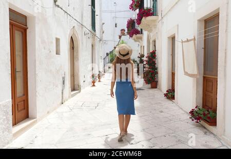 Rückansicht der jungen Touristenfrau auf der alten Straße in der Altstadt. Reisen Frau in Strohhut und blauem Kleid genießen Urlaub in Europa. Tourismus und Reisen Stockfoto