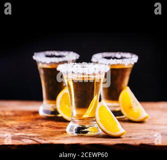 Baum Shot Gläser mexikanischer Tequila Cocktail mit Zitronenscheiben und Salz auf Holztisch mit schwarzem Hintergrund. Shooter Drink an der Bar für glücklich Stockfoto