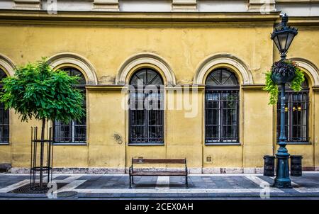 Budapest, Ungarn, Aug 2019, Blick auf eine Holzbank an einem Laternenpfosten in einer Straße der Hauptstadt Stockfoto