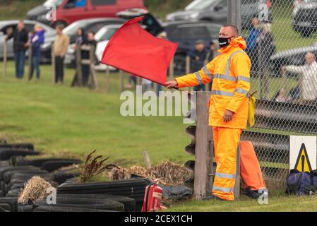 Marschall in Gesichtsmaske winkt rote Flagge, um das Rennen bei der 5 Nationen British Rallycross Veranstaltung in Lydden Hill, Kent, Großbritannien zu stoppen. Während COVID-19. Offiziell Stockfoto