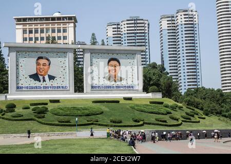Nordkoreaner im Zentrum Pjöngjangs, wo Porträts der verstorbenen Führer Kim Il-sung, links, und Kim Jong-il, im Hintergrund zu sehen sind Stockfoto