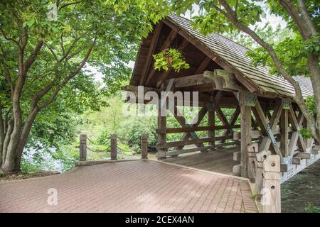 Altmodische überdachte Brücke mit Grünpflanzen über den DuPage River in Naperville, Illinois Stockfoto