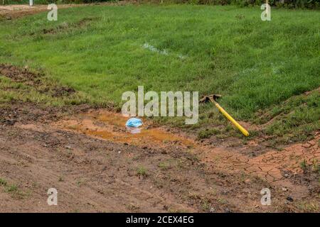 Eine Gesichtsmaske in einer schlammigen Pfütze von einem abgelegt Arbeiter auf einer Baustelle, die die Umwelt verschmutzt, ist ein Problem Während der kovid19 Pandemie Stockfoto