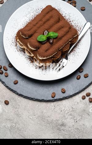 Klassisches Tiramisu Dessert auf Keramikplatte auf Betongrund Stockfoto