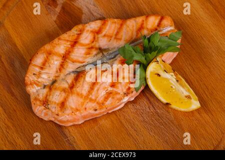 Gegrillter Lachs mit Zitrone und Petersilie auf dem Holzbrett serviert. Stockfoto