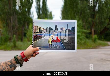 Ein Bild von jemandem zeigen ein Bild des Alten lebhaften Stadt Pripyat gegen die aktuelle aufgegeben Szenario. Stockfoto