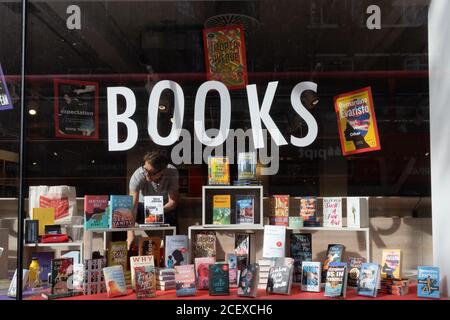 Foyles, ein Mitarbeiter des Londoner Buchhändlers, nimmt während der Coronavirus-Pandemie am 2. September 2020 Änderungen am Fenster des Bücher- und Literaturhändlers auf der Charing Cross Road vor, zu einer Zeit, in der nur einige Einzelhändler und Geschäfte wieder eröffnet werden, während Büroangestellte noch größtenteils von zu Hause aus arbeiten. In London, England. Stockfoto