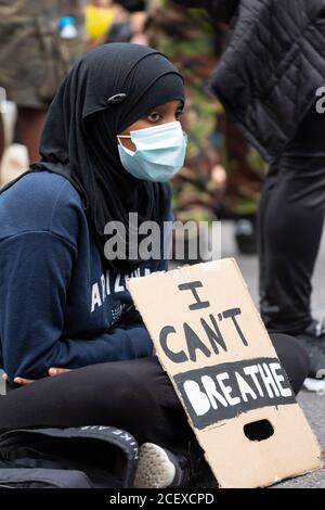 Ein junges muslimisches Mädchen sitzt mit einem Plakat auf der Million People March, London, 30 August 2020 Stockfoto