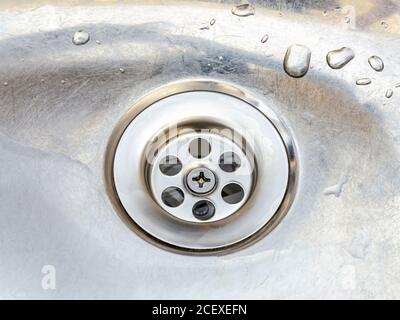 Neues Sieb in der alten Metallwaschbecken mit Wassertropfen. Installation, Reinigung und Reparatur von Haushaltsarmaturen. Stockfoto