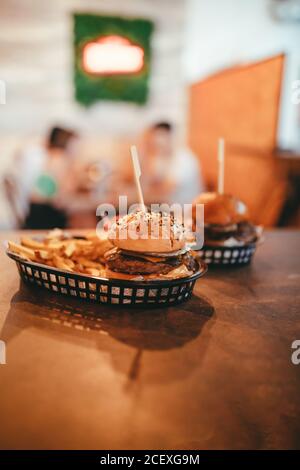 Appetitlich frische Burger mit Rindfleisch und Käse serviert mit Französisch Pommes im Plastikfach im Café Stockfoto