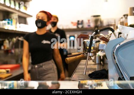 Unerkennbar verschwommene Barkeeper in medizinischen Masken arbeiten in modernen Kaffee Shop während COVID 19 Ausbruch Stockfoto