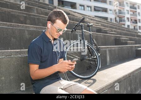 Junger Mann mit Handy und Fahrrad sitzend Betontreppen Stockfoto