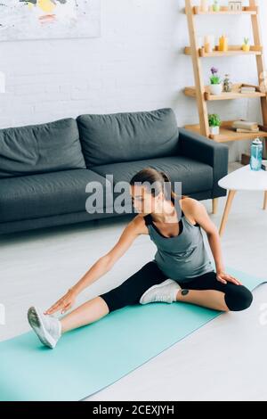 Schwangere Frau in Sportkleidung Stretching auf dem Boden zu Hause Stockfoto