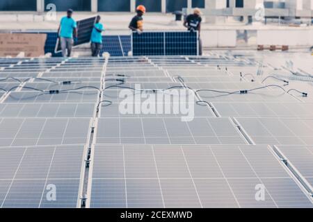 Moderne Solarpaneele in Reihen im industriellen Bereich von installiert Fabrik auf dem Hintergrund der nicht erkennbaren ethnischen Arbeiter Stockfoto