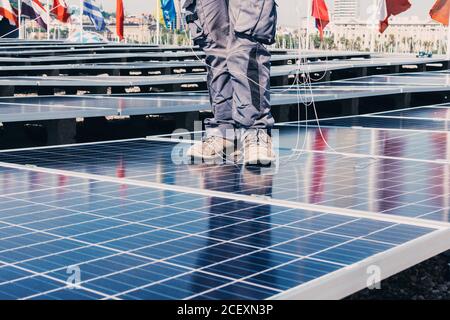 Crop anonymen männlichen Arbeiter in Uniform stehen auf Solarpanel Während der Installation im industriellen Bereich der modernen Anlage Stockfoto