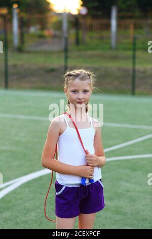 Das Mädchen sitzt auf dem Garn auf dem Sportplatz Stockfoto