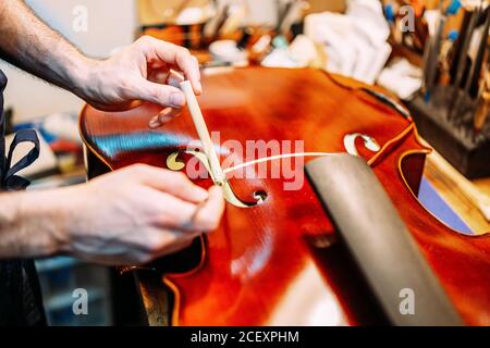 Crop anonyme Handwerker Einstellung Sound Post beim Bau Saiteninstrument In der Werkstatt Stockfoto