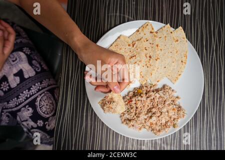 Crop ethnischen weiblich genießen köstliche Mas Huni mit Chapati Brot Während des Frühstücks am Tisch im Restaurant Stockfoto