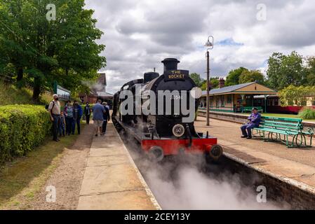 Passagiere auf dem Bahnsteig neben der schwarzen Dampflokomotive Rocket auf der Bluebell Heritage Eisenbahnlinie, Horsted Keynes, West Sussex, England, Großbritannien Stockfoto