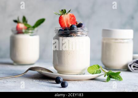 Hausgemachter Cashew veganer Joghurt auf Gläsern auf Weiß serviert Rustikaler Tisch Stockfoto