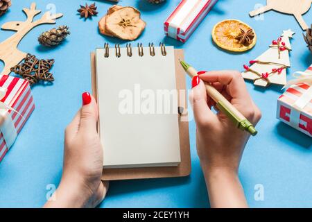 Blick von oben auf die weibliche Hand einige Tasten an noteebok auf blauem Hintergrund. Neues Jahr Dekorationen und Spielzeug. Weihnachten Konzept. Stockfoto