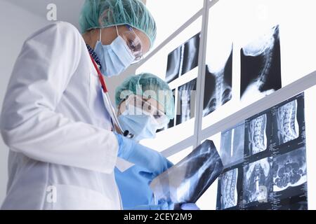 Zwei medizinische Arbeiter in schützenden medizinischen Masken und Handschuhe und Brillen untersuchen Röntgenstrahlen Stockfoto