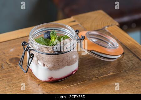 Nahaufnahme von Glas mit köstlichen Schokolade Mousse garniert Heidelbeeren und Zweig der Minze und auf Holztisch platziert Im Café Stockfoto