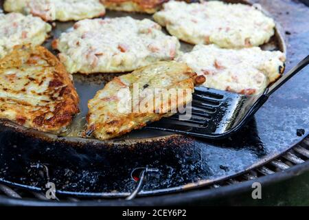 Gebratene Kartoffelpfannkuchen auf dem Grill. Ungesunde fetthaltige Lebensmittel. Bratkartoffeln Pfannkuchen in der Pfanne braten Stockfoto