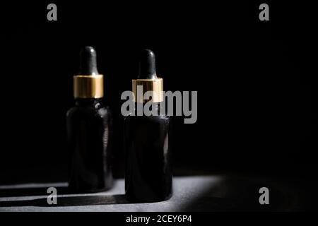 Pipette schwarze Glas Tropfflasche mit goldenen Elementen auf der Dunkler Hintergrund Stockfoto