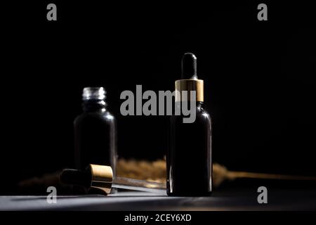 Pipette schwarze Glas Tropfflasche mit goldenen Elementen auf der Dunkler Hintergrund Stockfoto