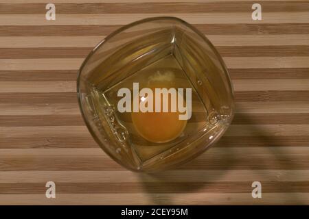 Rohes Ei in einem Glasbecher. Auf einem Holzbrett Stockfoto