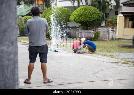 Bruch der Wasserleitung. Wasser fließt in einen Brunnen. Versorgungsarbeiter hält Schraubenschlüssel und in Graben reparieren die gebrochene Pip. Stockfoto