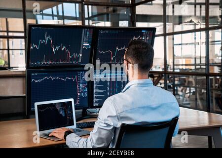 Trader sitzt im Büro und analysiert den Index auf dem Kryptowährungsdiagramm Stockfoto